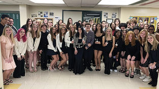 A group of Carlynton Junior Senior High School students dressed in formal attire, smiling and posing together indoors before their National Honor Society induction ceremony in November. The students represent the values of scholarship and leadership highlighted in the article.