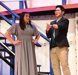 A man and woman stand on stage with a staircase behind them, performing in Greensburg Salem High School's spring musical.