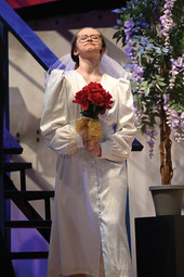 A woman in a white dress is holding a bouquet of red roses.