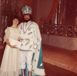The author in a long dress posing with the Mardi Gras King