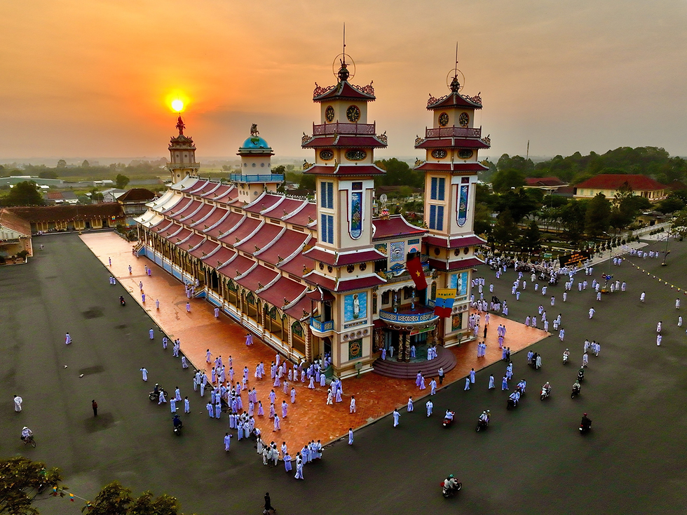 Worshippers gather at the Cao Dai Holy See in Tay Ninh, Vietnam, as the sun sets, highlighting the vibrant architecture of this spiritual site.