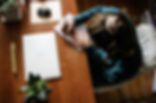 Small business owner writing in a notebook at a wooden desk with a laptop, mouse, green plant, and white chair. Bright, organized workspace for a small business owner in Harrisburg, Pennsylvania.