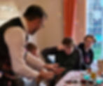 Young adults look on in amazement as Mark performs a magic trick in a guests hands