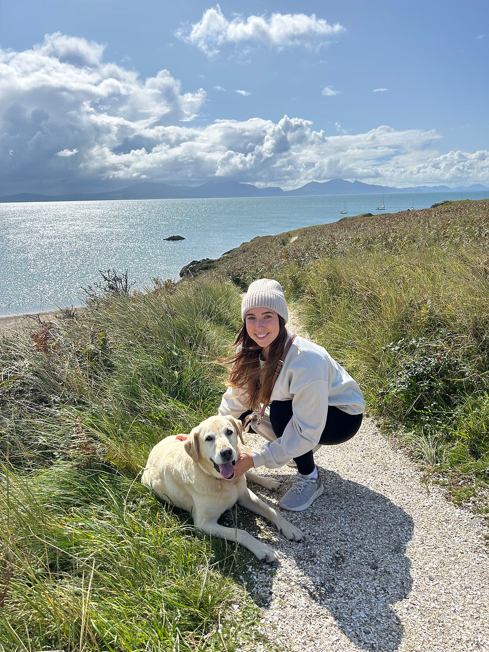 Isabelle Hanby with a Labrador on a coast path with the sea in the backgroun