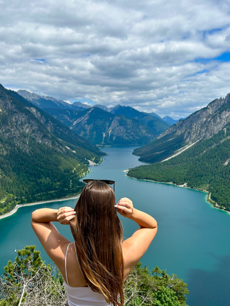 Frau steht vor See mit Gebirge im Hintergrund in Österreich
