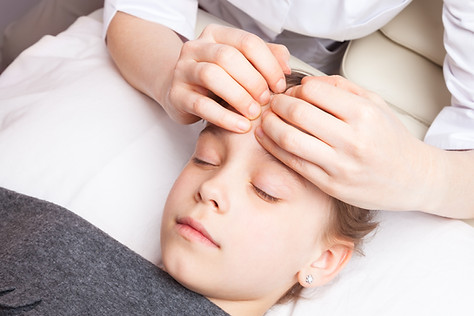 Die Anwendung der Craniosakral Therapie am Kopf eines Kindes. Heilpraktiker Praxis Muenchen.