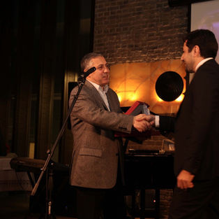 Two men in suits shaking hands during an award event.