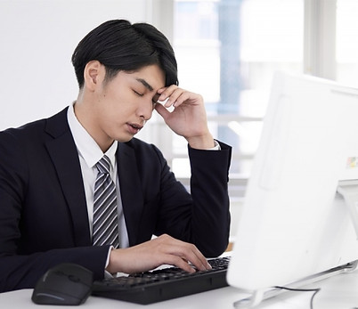 額に手をあてて目をつぶっている男性