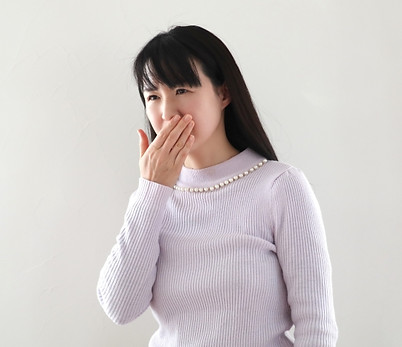 口に手をあてて気分悪そうにしている女性