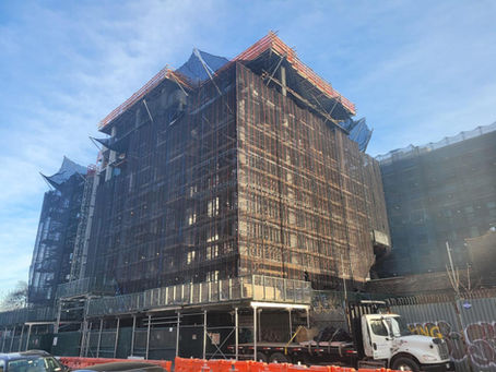 NYC building with pipe scaffolding and a sidewalk shed.