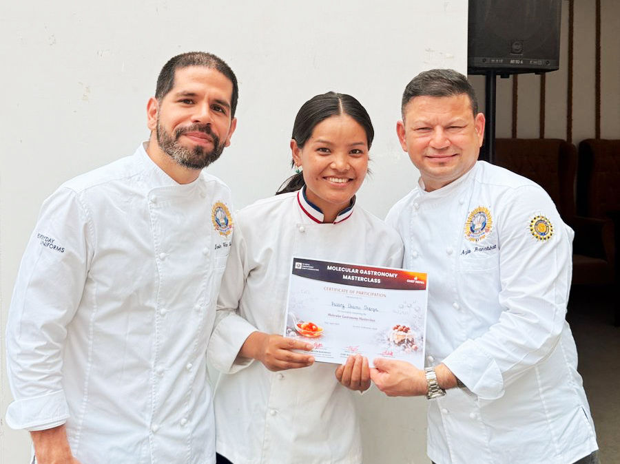 Chef Arjun Ranabhat and Chef Irvin Van Oordt with Sherpa Cuisine Chef Pasang Lhamu Sherpa in white uniforms smile, holding a "Molecular Gastronomy Masterclass" certificate indoors with a neutral background.