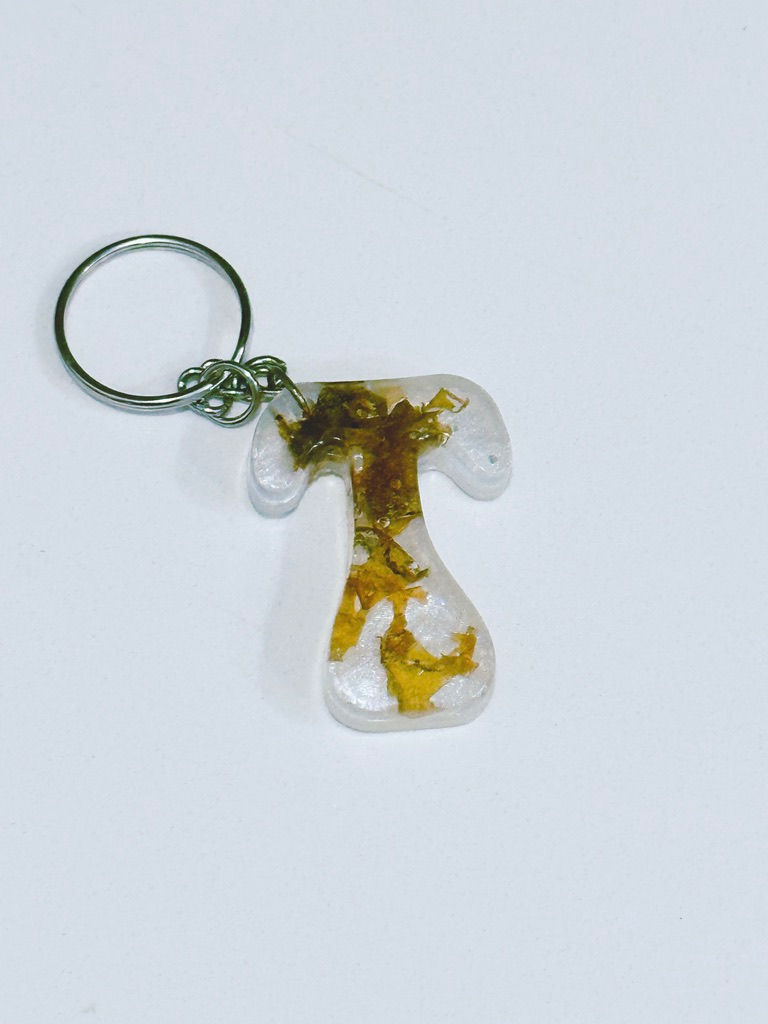 Thumbnail: Letter T epoxy resin keychain infused with broken seaweed on a pearly white backdrop