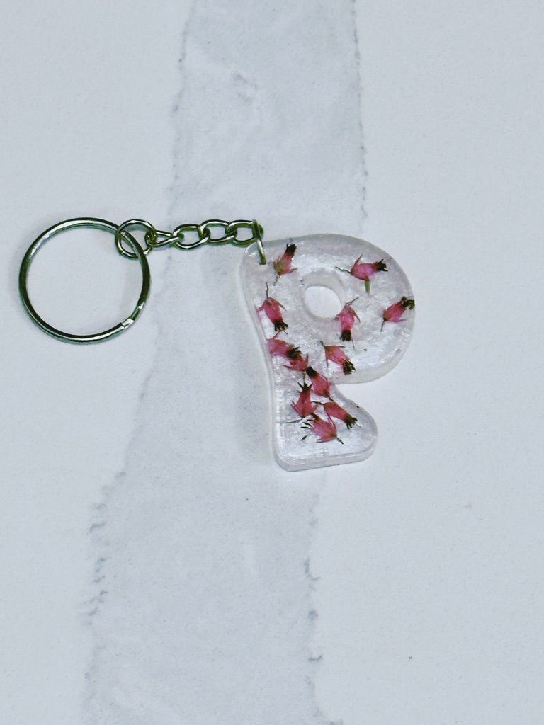 Thumbnail: Letter P epoxy resin keychain infused with real Heather blooms on pearly white backdrop