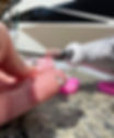 sanding down the edges of an epoxy resin keychain after the back of the flowers were sanded down to make the back of the resin keychain smooth