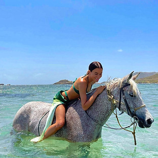 Woman sitting on a horse in the ocean in St. Lucia at Sandy Hoofs St. Lucia Riding Stables