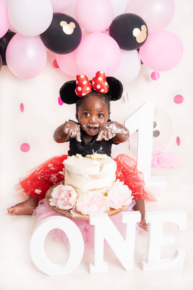Baby girl celebrating her first birthday with a cake smash