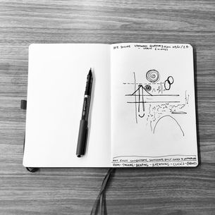A black and white photo of an open sketchbook with a visual score of mark making on the pages. Each page details the time and place of listening at the top and what was heard and felt along the bottom.