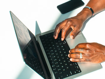 professional black man hands corporate entrepreneur library wearing cross typing designing on macbook apple computer in Columbus Ohio lifestyle branding photography by emerging artist Zari Nelson. 