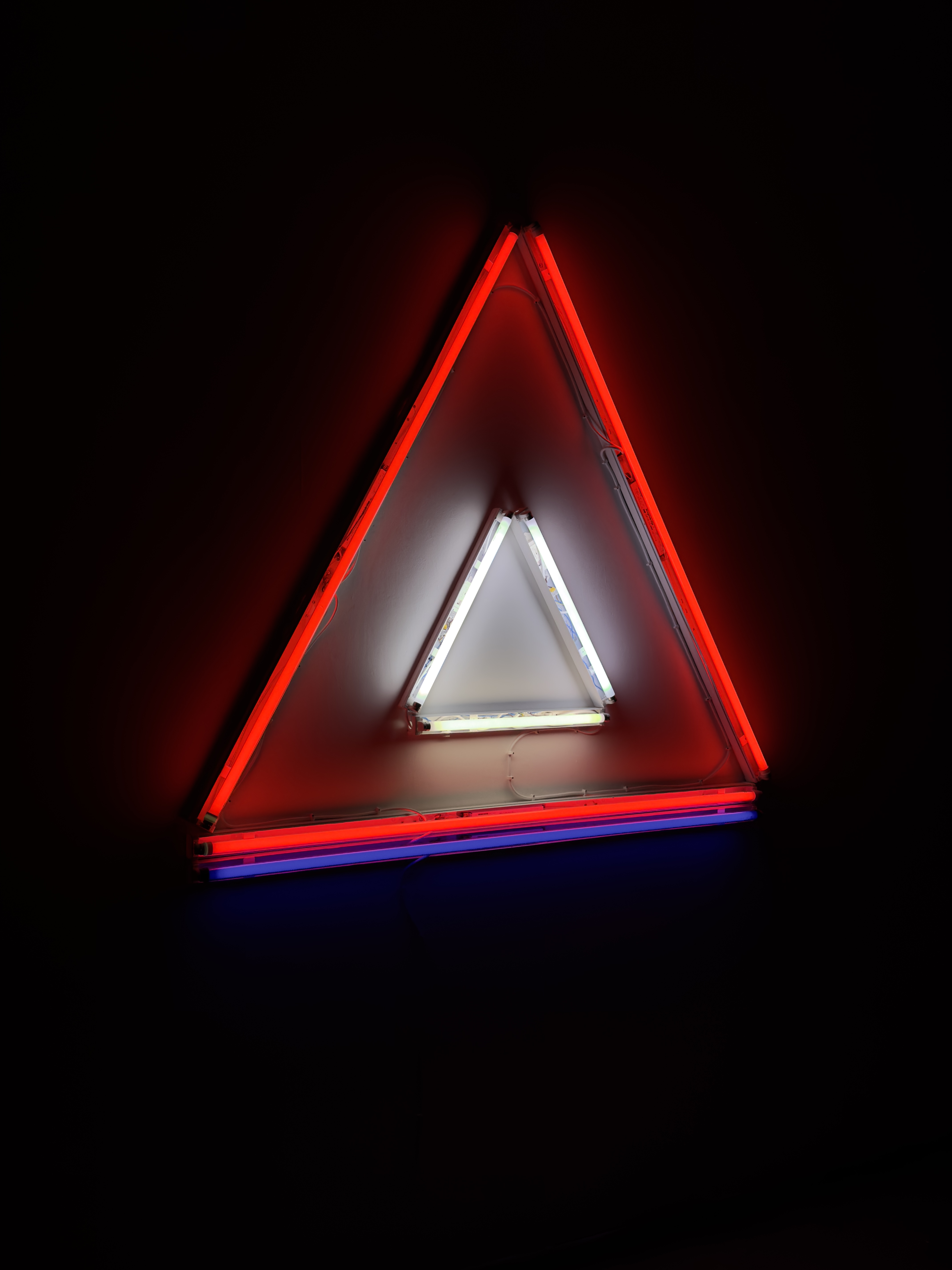 Madonna and Child II, a large red fluorescent triangle, with a small white fluorescent triangle nested inside of it and a long blue fluorescent light below it