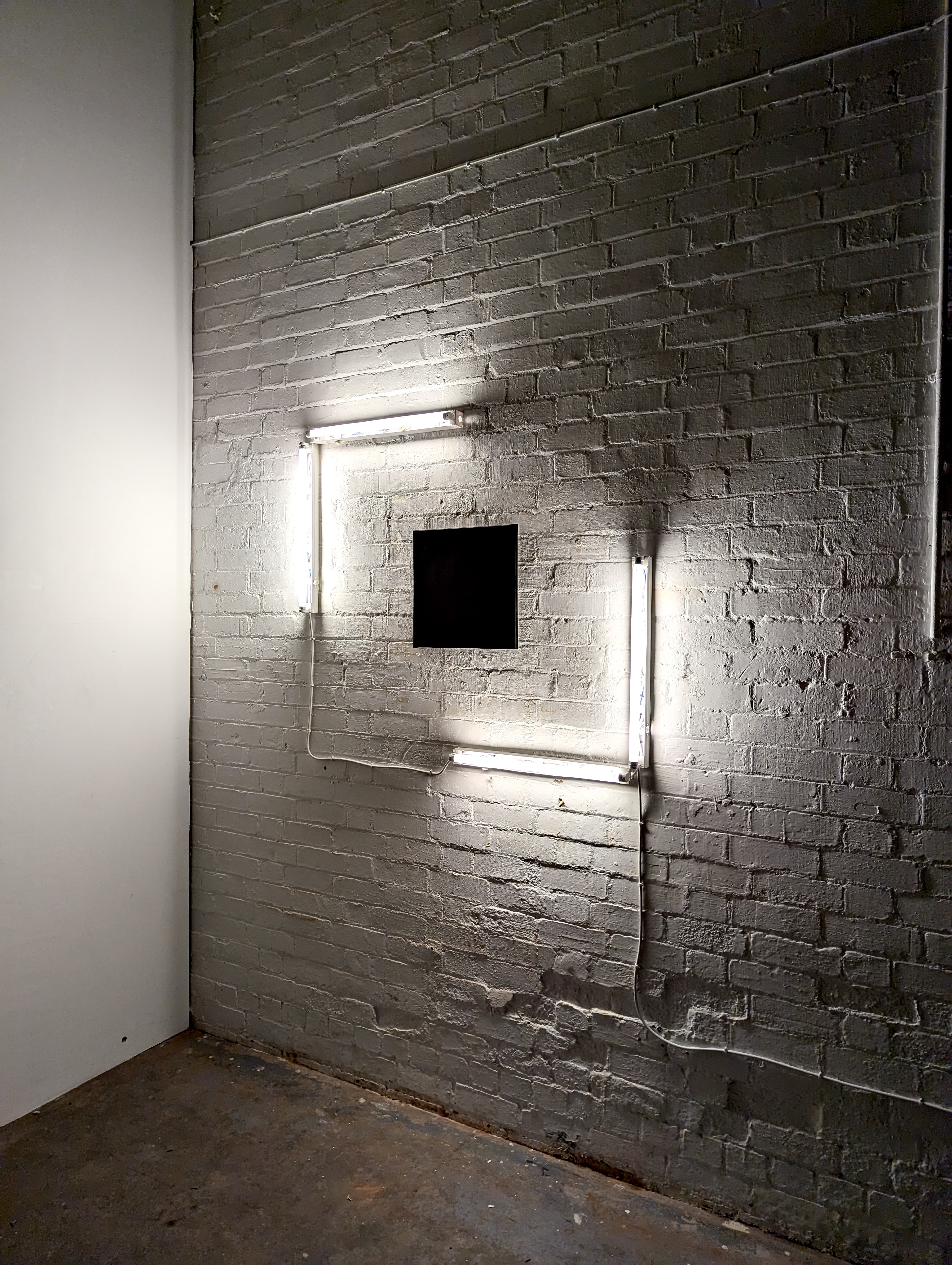 A black canvas surrounded by white fluorescent light