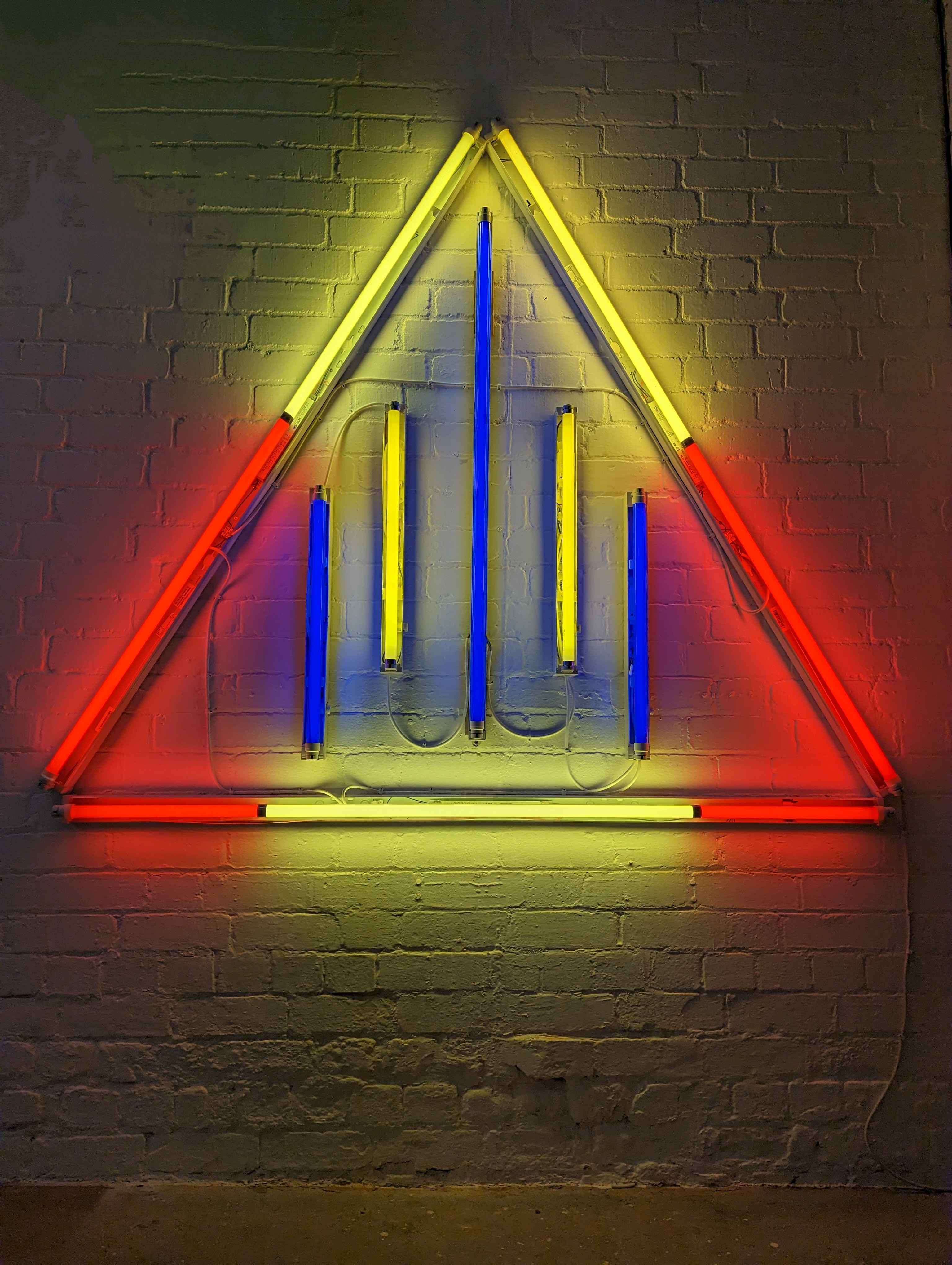 Lines of blue and yellow fluorescent light inside a red and yellow fluorescent triangle
