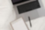 kaboompics_working-with-a-laptop-in-bed-white-cotton-bedding-blank-notebook-pen-28939.jpg