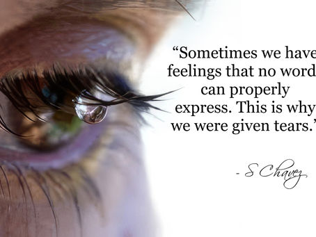 close up of an eye with a tear hanging from the upper lashes