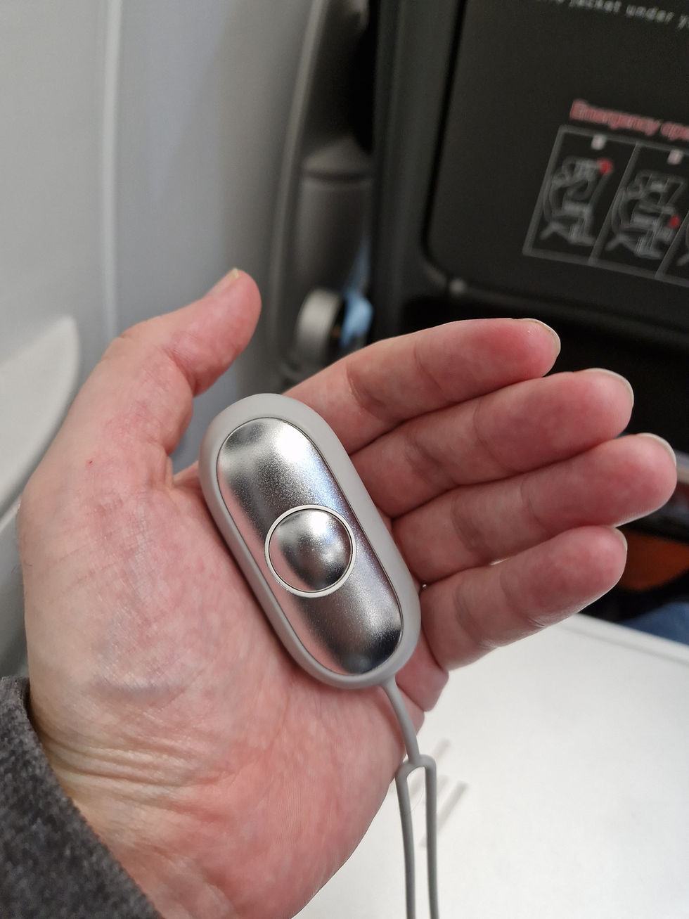 A CalmCarry device in a person's hand on an airplane.