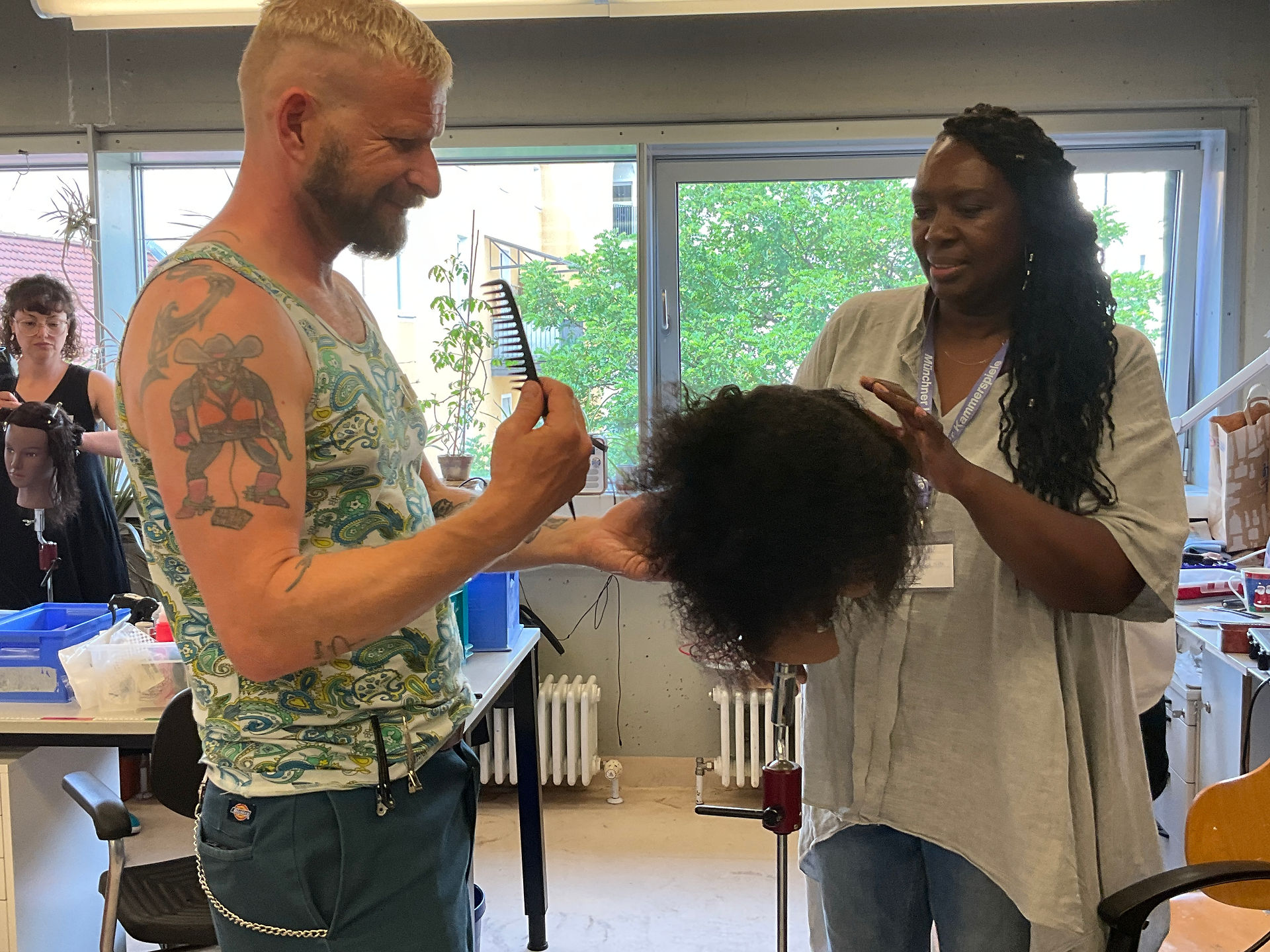 hair dresser teaching a man with tattoos how to style hair 