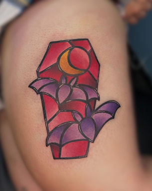 A vibrant and detailed stained glass-style bird tattoo on someone's shoulder, featuring shades of red, purple, and yellow. This artwork was expertly created by a talented tattoo artist at one of the best tattoo shops in Lubbock.