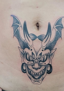 A striking and intricate tattoo of an intense Japanese oni mask on the ribcage, showcasing detailed horns, fierce facial features, and flowing hair, expertly created by a skilled tattoo artist at the best tattoo shop in Lubbock.