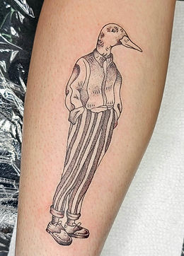 A playful and unique black-and-white tattoo on the leg featuring an anthropomorphic bird dressed in a collared shirt, vest, striped pants, and shoes, beautifully crafted by an expert tattoo artist at the best tattoo shop in Lubbock.
