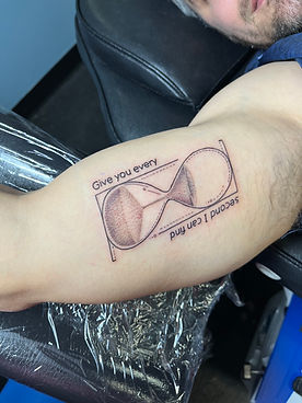 A unique and personalized tattoo on the forearm featuring a stylized graphic of sunglasses with the text 'Give you every second I can find.' This thoughtful design was crafted by a skilled tattoo artist at one of the best tattoo shops in Lubbock.