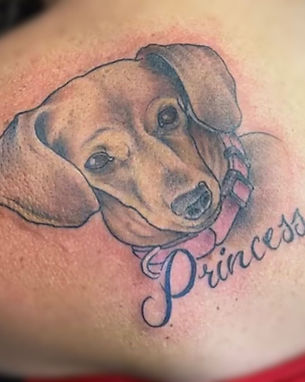 A heartfelt and detailed puppy tattoo wearing a pink bow and collar, with the name 'Princess' elegantly scripted nearby, crafted by a talented tattoo artist at one of the best tattoo shops in Lubbock.
