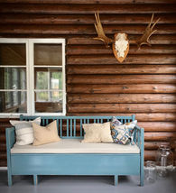 Custom linen bench cushion in a rustic Swedish summer house, blue wooden bench against log walls, verified customer Ida from Sweden, LinenSpace.
