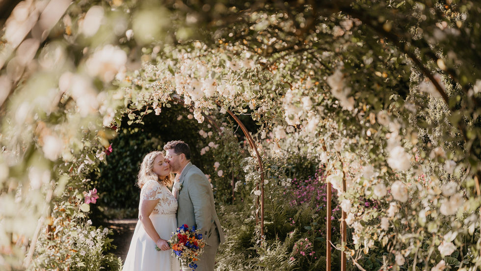 Couple stood in flower archway tunnel, Hotel Endsleigh gardens,Wedding