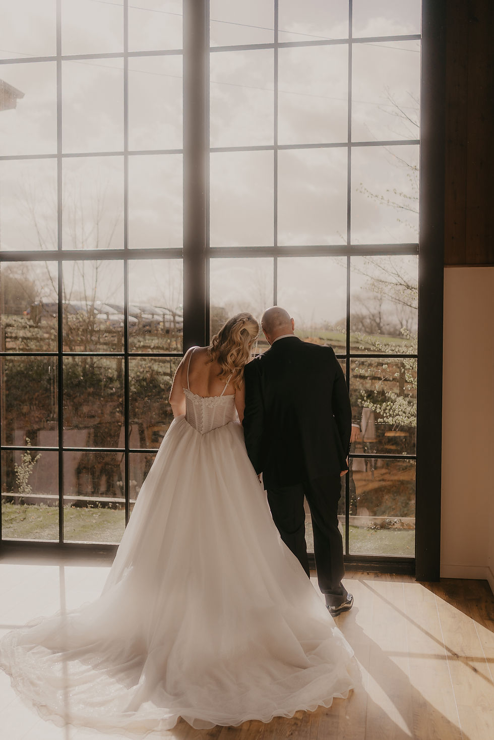 wedding photo of couple in large black framed window at Upton Barn wedding venue in cullompton devon