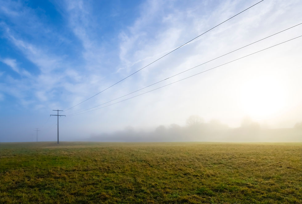 Overhead power line with wooden poles and electric wires spanning over rural landscape on