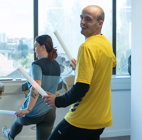 A neurodiverse man in yellow top dancing and raving as a form of exercise with his mentor