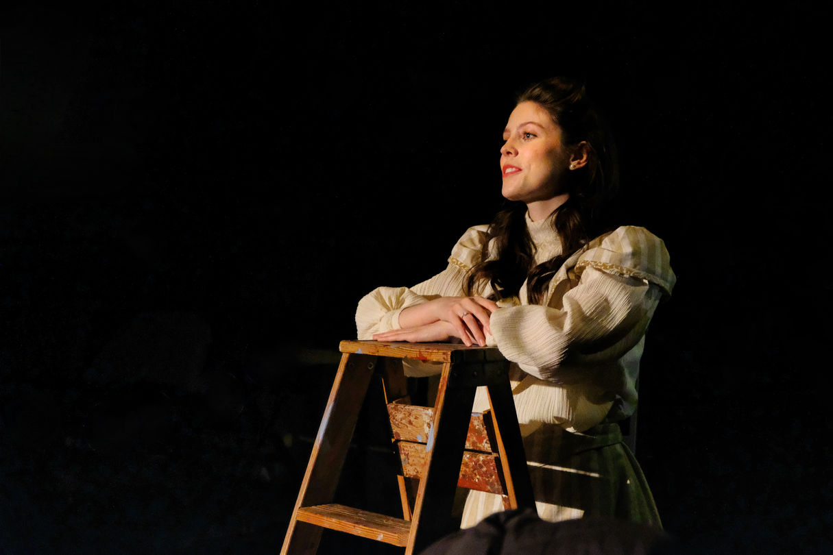 Emily on ladder in the audience aisle