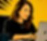 Image shows Zara Malley sitting working on her macbook in her office