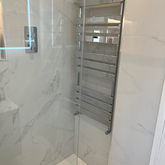 En-Suite bathroom interior using Palatina Blanco Brillo, gloss white, large format, marble tiles with chrome fixtures.