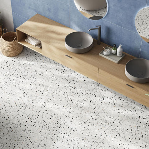 Blue paint chips make up a terrazzo porcelain tile in a bathroom setting.