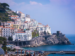 Amalfi Coast town built into a cliffside overlooking a clear blue sea.