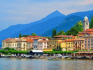 Bellagio, Lake Como, Italy, with colorful buildings, a church tower, and mountains under a blue sky.