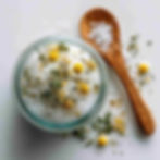 bath salt made with Epsom salt with camomile in a glass jar and a wooden spoon placed next to it