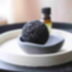 large round lava rock on a grey concrete tray with a small bottle of essential oil in the background