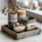 A set of decorative home accessories styled on a rustic wooden tray: a candle holder, a trinket dish, and a small sculptural ornament - all uniquely hand-painted with layered concrete-effect paint in shades of grey, clay, and taupe.