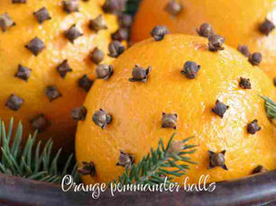 close-up of 3 orange pomander balls studded with whole cloves