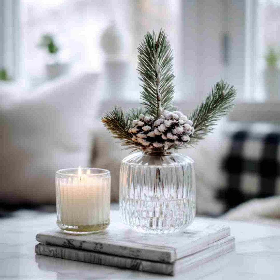 Scandinavian-style modern table decoration with a glass vase, pine tree, and white candle placed on two books